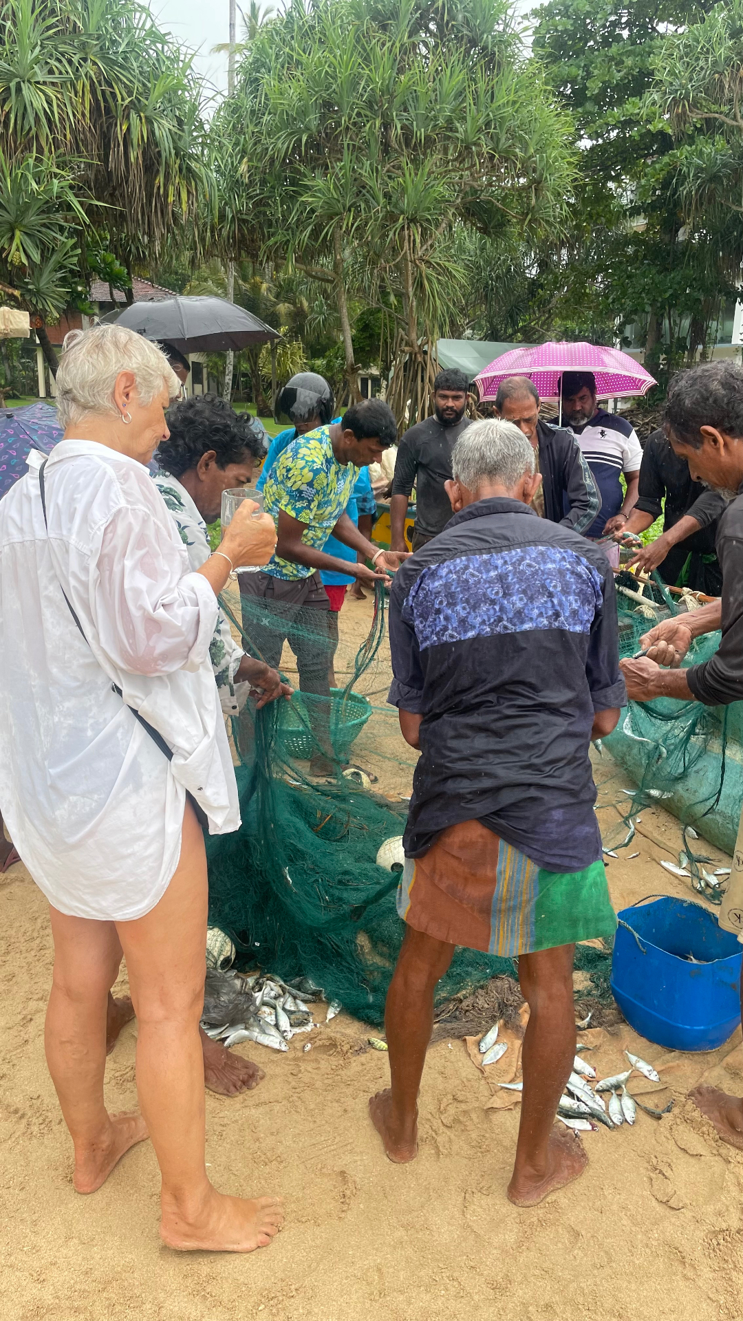 Local fishermen sorting their catch on the beach in Talalla, joined by a Bird Phoenix volunteer